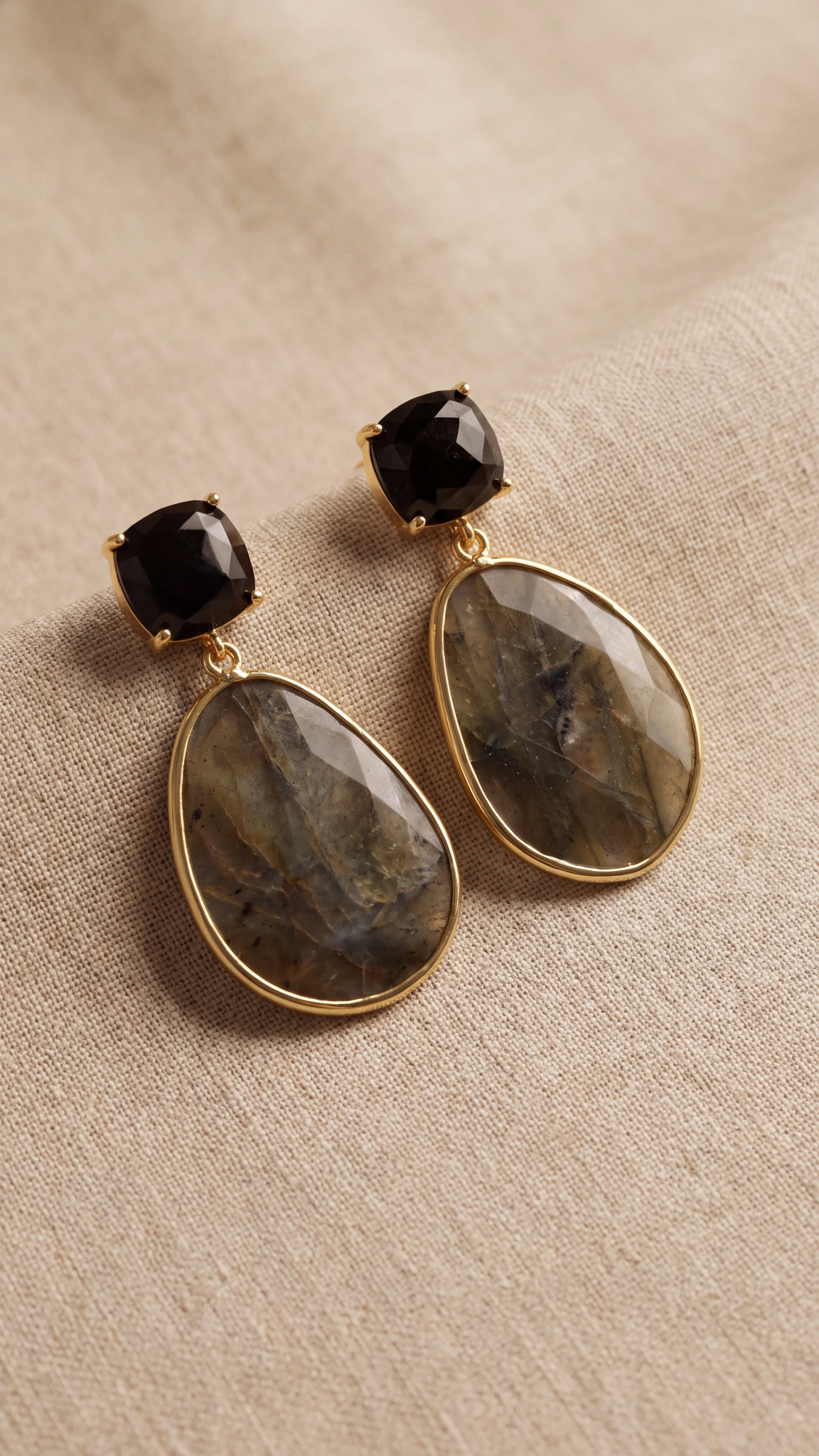 Par de pendientes de labradorita natural con acabado dorado sobre fondo textil beige