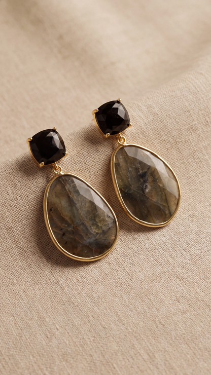 Par de pendientes de labradorita natural con acabado dorado sobre fondo textil beige